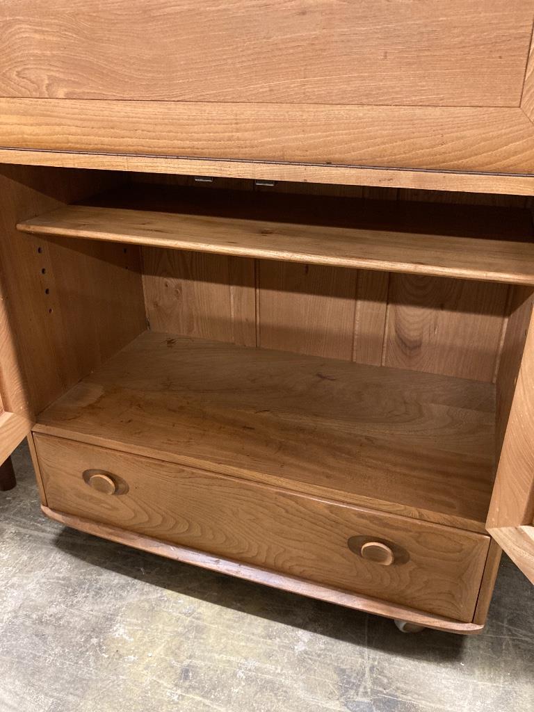 An Ercol elm fall front cabinet, width 82cm depth 44cm height 110cm